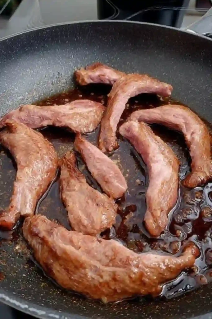 Aiguillettes de canard en cours de cuisson dans une poêle chaude avec jus caramélisé