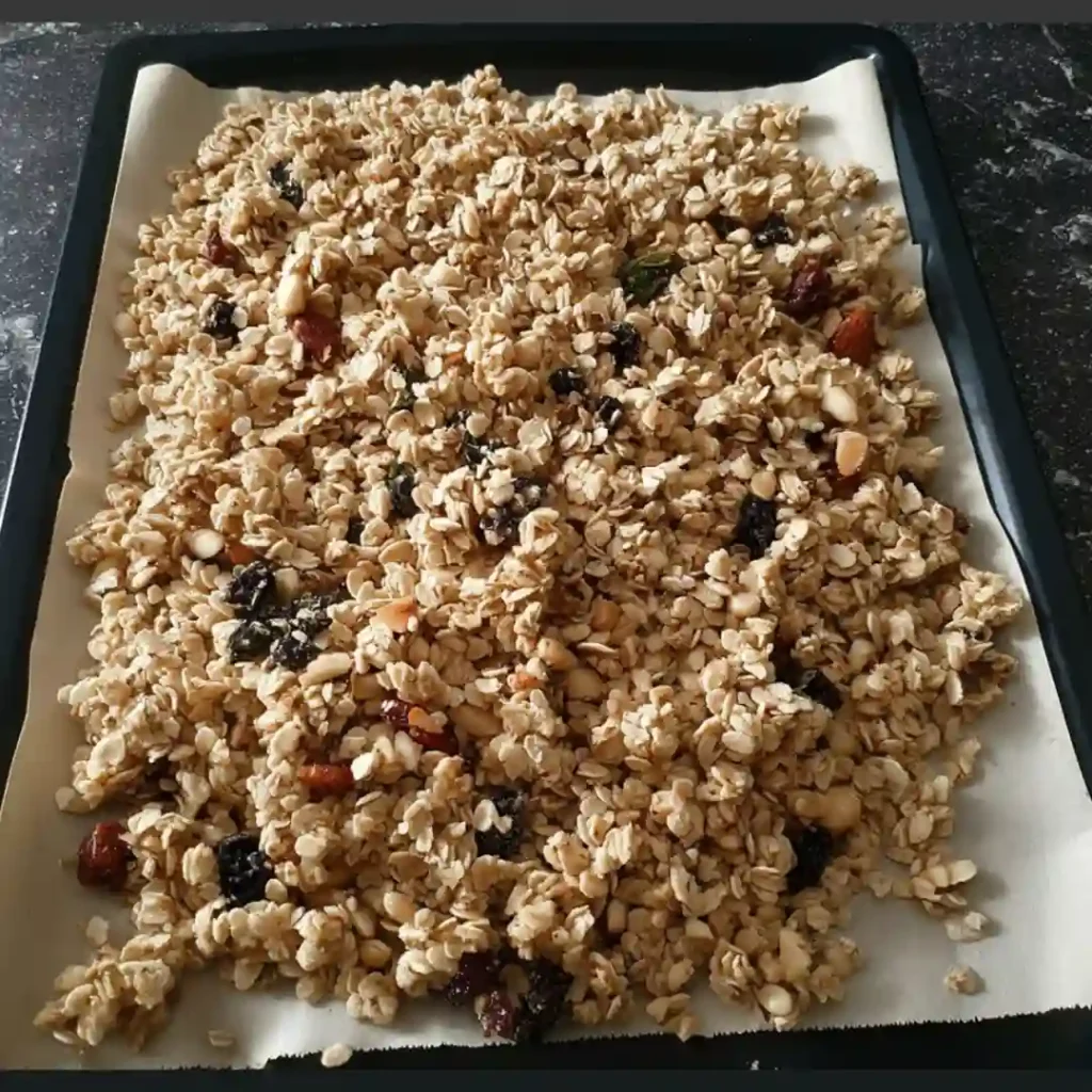Granola sans sucre ajouté étalé et tassé sur plaque recouverte de papier cuisson