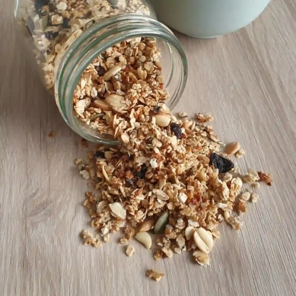 Granola sans sucre ajouté refroidi versé depuis un bocal en verre