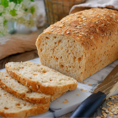 Pain de mie complet maison doré et moelleux, tranché sur une planche, idéal pour le petit-déjeuner ou les sandwichs maison.