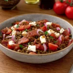 Salade de lentilles aux tomates, feta et oignons rouges servie dans un bol, recette équilibrée et riche en protéines végétales.