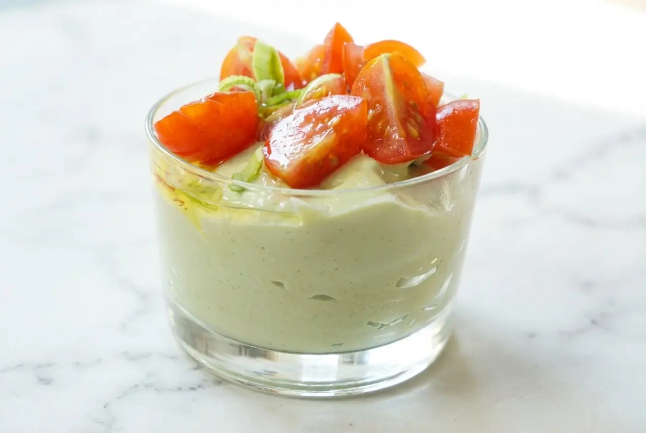 Mousse d'avocat au fromage blanc onctueuse en verrine, zestes de citron vert et pointe de raifort sur marbre blanc.