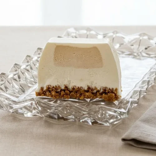 Recette de bûche glacée vanille-caramel sur un plat de service, avec une tranche coupée révélant un cœur caramel fondant et une base