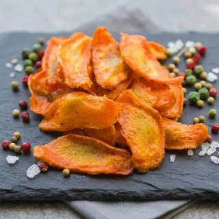 Chips de carotte au four croustillantes et finement dorees disposees dans un bol en ceramique pour l'aperitif.