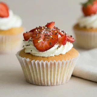 Cupcakes à la fraise décorés d'un glaçage mascarpone onctueux et de perles multicolores.