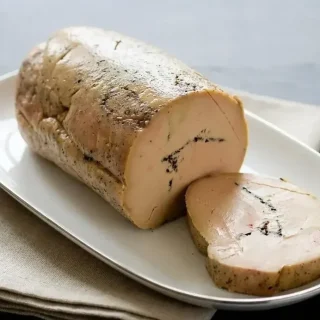 Terrine de foie gras aux truffes coupée en tranches épaisses dévoilant un marbrage de brisures de truffe noire
