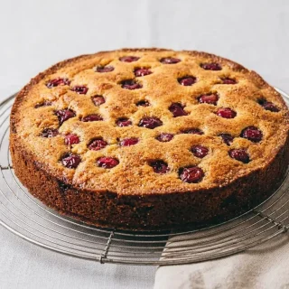 Gâteau aux cerises moelleux et doré parsemé de cerises entières brillantes juste après cuisson