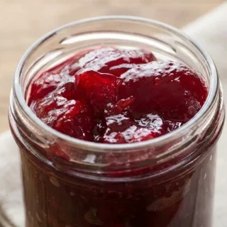 Gelée de fruits rouges brillante et limpide dans un pot en verre.
