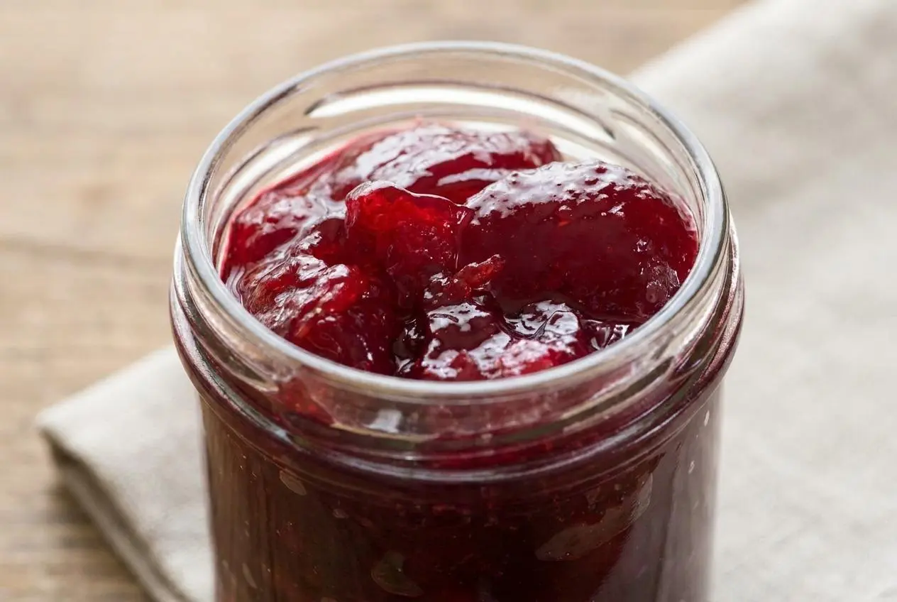Gelée de fruits rouges brillante et limpide dans un pot en verre.