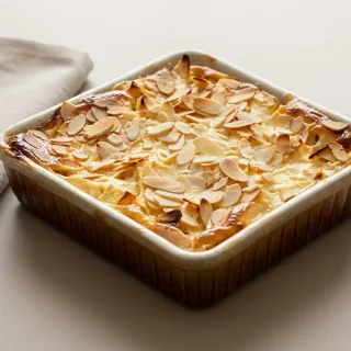 Gratin de pommes doré au four surmonté d'amandes effilées grillées dans un plat en céramique