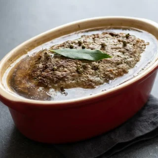 Terrine de pâté de foie de volaille traditionnel tranché dans son plat en grès