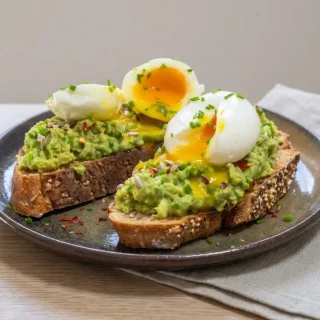 Tartines Avocat et Oeuf Mollet sur pain de campagne croustillant avec écrasé d'avocat crémeux et oeuf coulant.