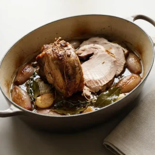 Rôti de porc en cocotte doré et tranché avec son jus de cuisson parfumé au thym et à l'ail