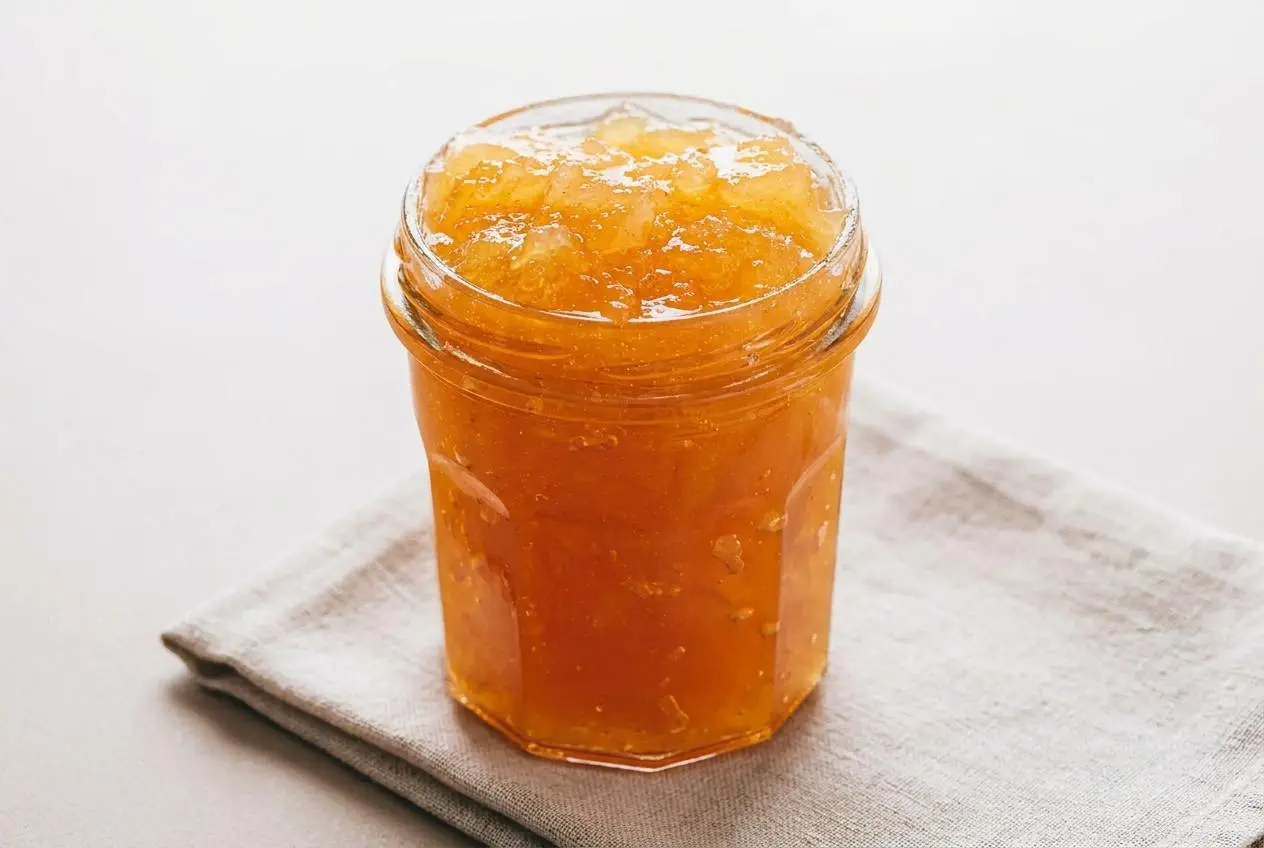 Confiture de pommes maison aux morceaux fondants et translucides dans un bocal en verre.