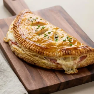 Feuilleté jambon fromage doré et croustillant garni de gruyère fondant et de jambon.
