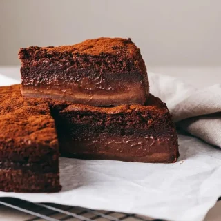 Part de gâteau magique au chocolat aux trois textures fondantes, poudrée d'un voile de cacao amer.