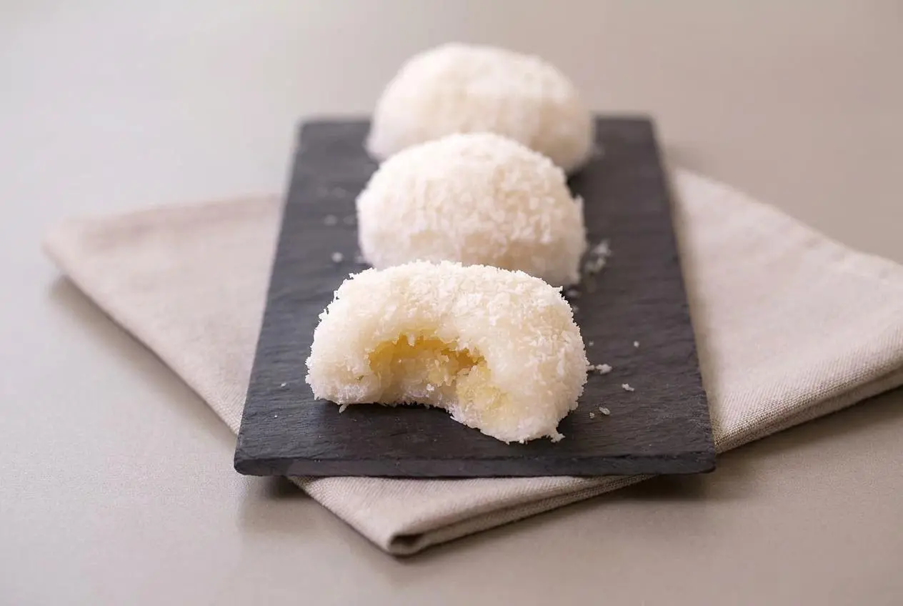 Perles de coco vapeur moelleuses enrobées de noix de coco râpée sur un plat de service