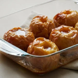 Pommes au four dorées et fondantes dans leur jus ambré caramélisé au beurre.