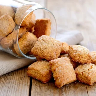 Recette des Canistrelli croustillants et dorés, parsemés de sucre cristal sur une assiette.