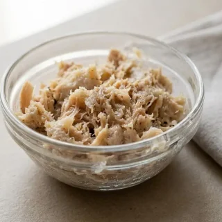 Terrine de rillettes de poulet maison à la texture fondante et filandreuse sur du pain de campagne.