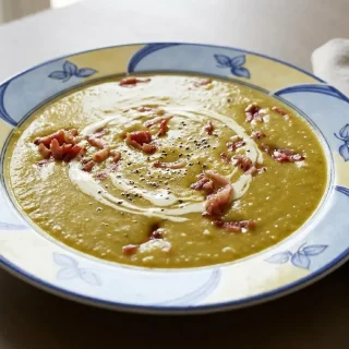Soupe de pois cassés crémeuse et fumée servie dans un bol avec une pointe de crème.
