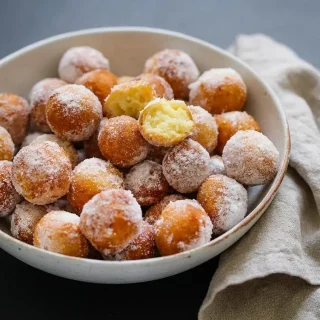 Beignets à la ricotta dorés et ronds, enrobés de sucre semoule croquant.