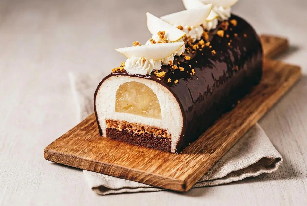 Bûche poire chocolat entière nappée d'un glaçage miroir cacao brillant sur son plat de service