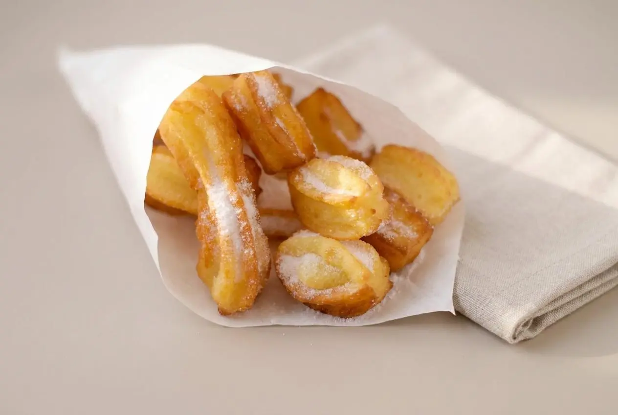 Bâtonnets de churros maison dorés et croustillants saupoudrés de sucre fin.