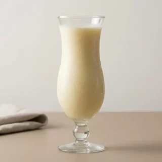 Recette Piña colada onctueuse servie dans un verre givré avec crème de coco et quartier d'ananas frais.